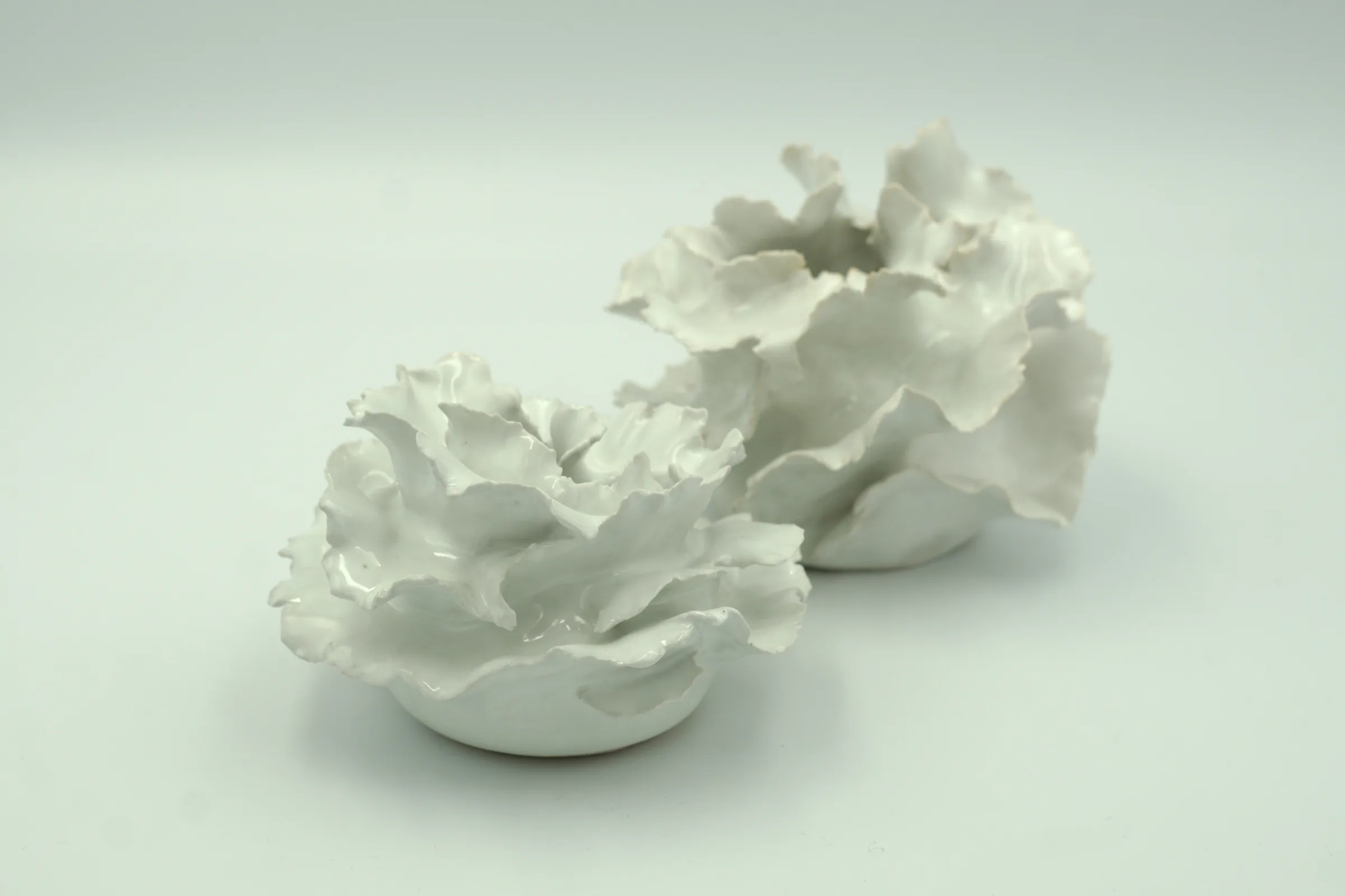 Pair of Krysta Mae ruffled white porcelain vessels on a soft grey surface