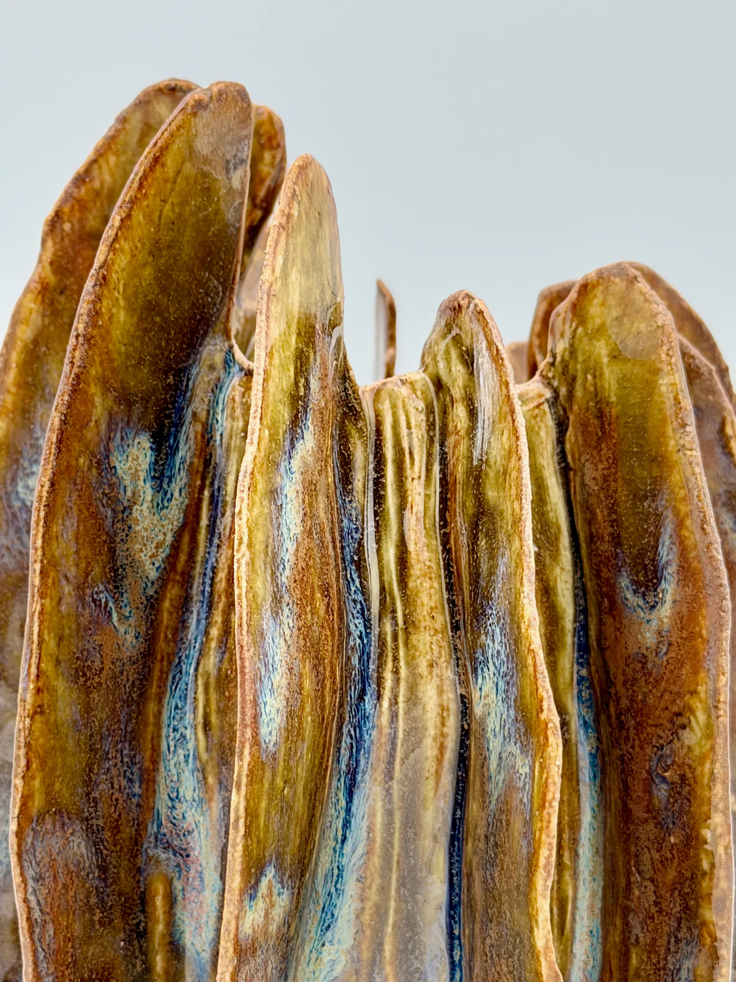 A bronze and blue ribbed sculpture with tall vertical fins