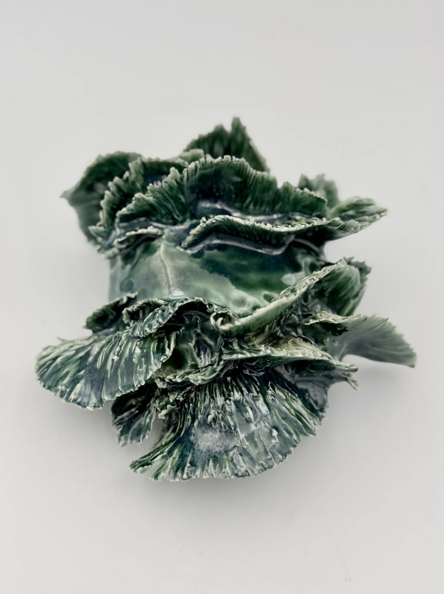 A green ruffled sculpture with layered, leaf-like folds